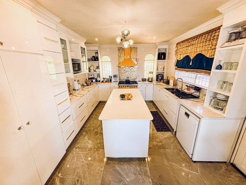 A well-appointed kitchen featuring a central island, stone countertops, white cabinetry, and high-end built-in appliances with elegant tiled flooring.