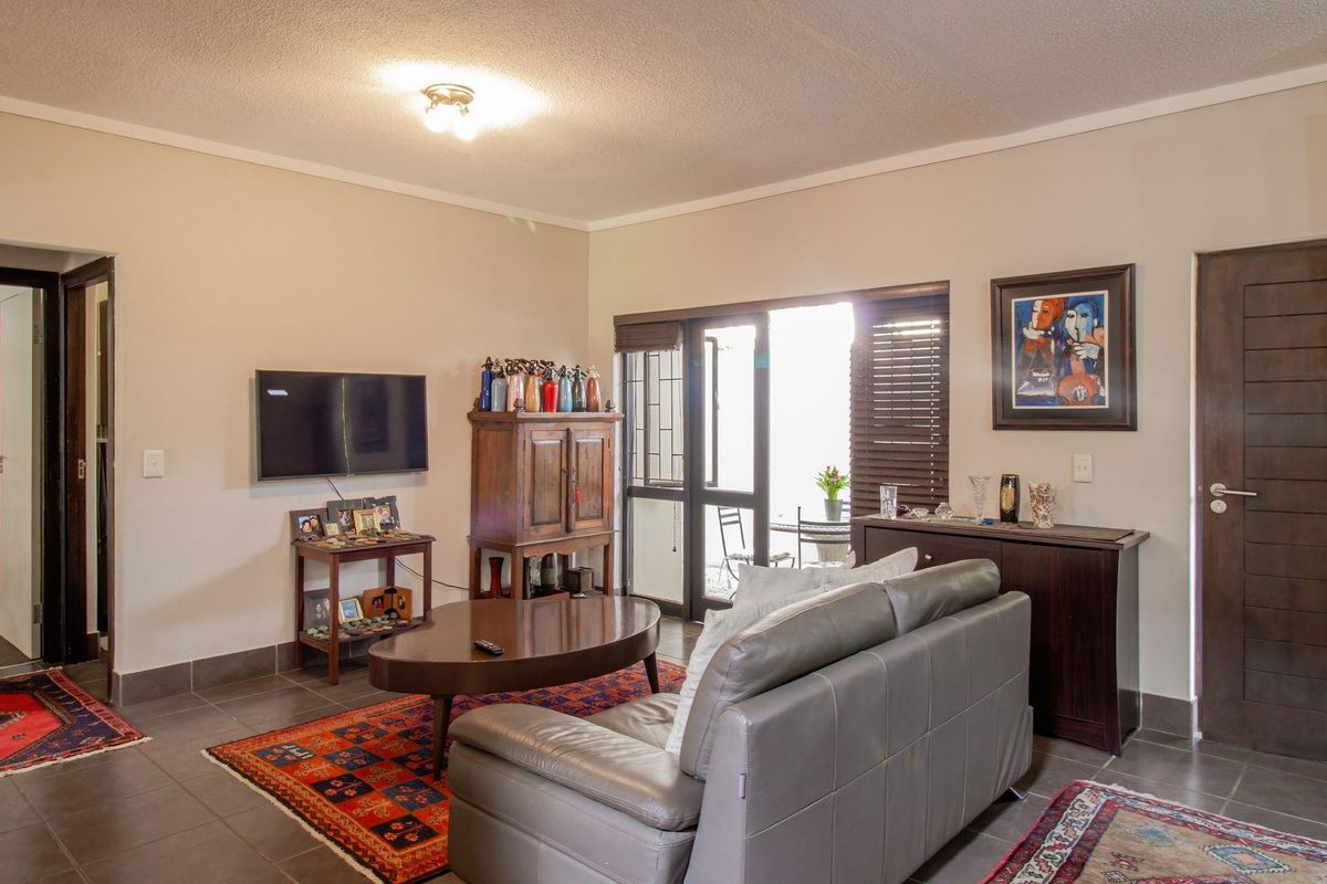A living room featuring tiled flooring, a textured ceiling, and a glass door providing access to an outdoor patio area.