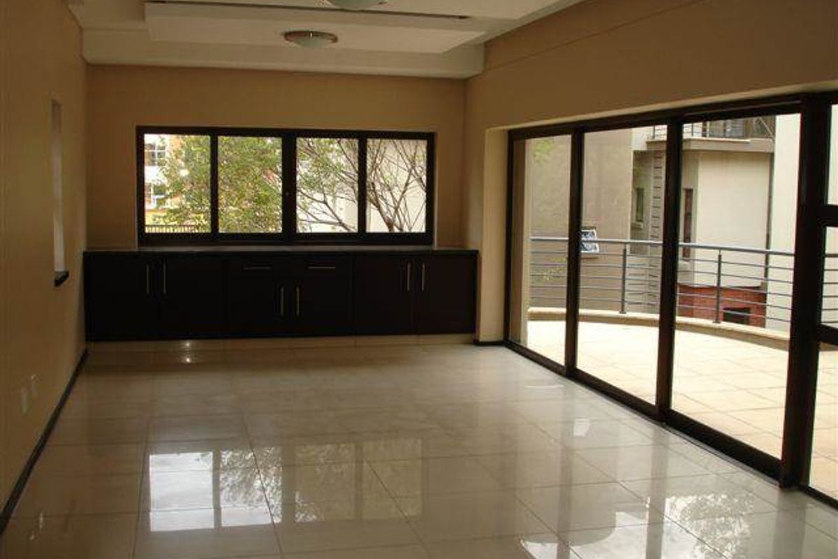Spacious living area featuring polished tile floors, built-in storage cabinetry, recessed ceiling lights, and large sliding glass doors opening onto a private balcony.