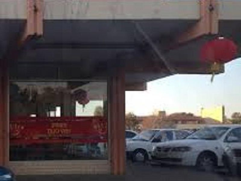 Front exterior view of a commercial storefront featuring a covered entrance canopy and large display window.