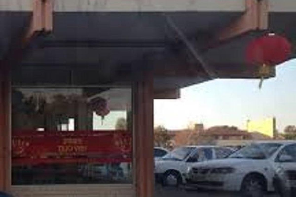 Front exterior view of a commercial storefront featuring a covered entrance canopy and large display window.