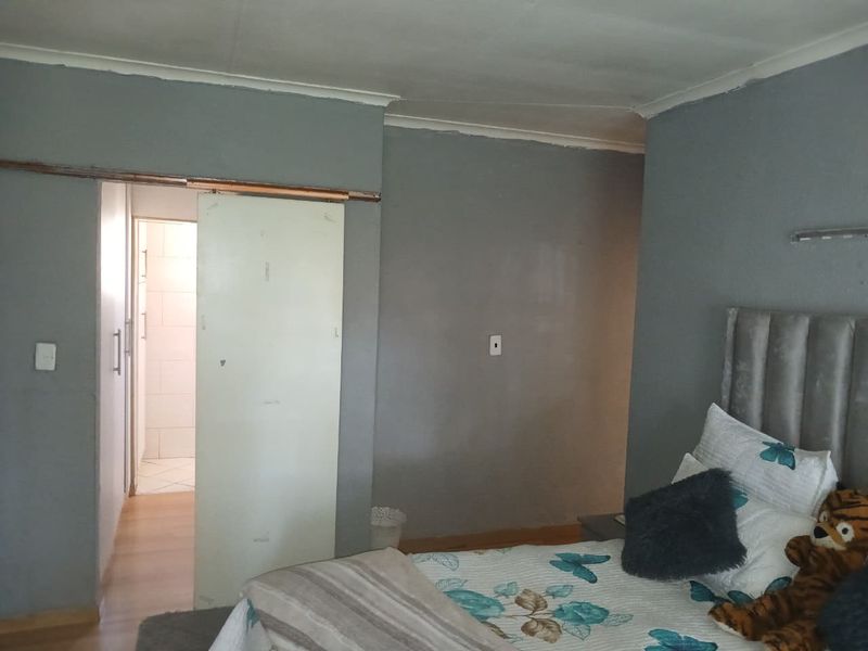 A bedroom featuring a sliding door leading to an adjacent space, with grey painted walls and standard ceiling coving.