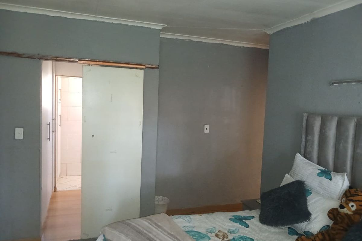 A bedroom featuring a sliding door leading to an adjacent space, with grey painted walls and standard ceiling coving.