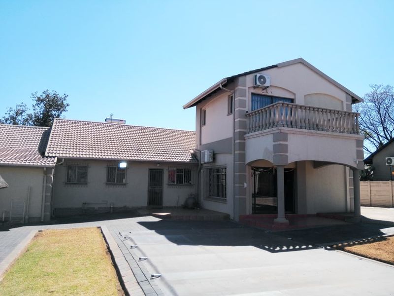 Front view of a double-story residential house featuring a paved driveway, balcony, and tiled roof structure.