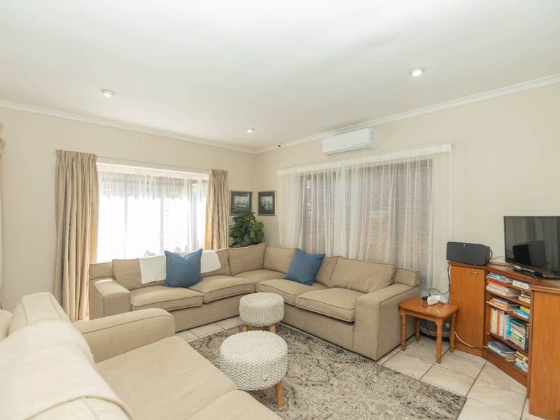 A comfortable living room featuring tiled flooring, recessed downlighting, and a wall-mounted split-system air conditioner for climate control.