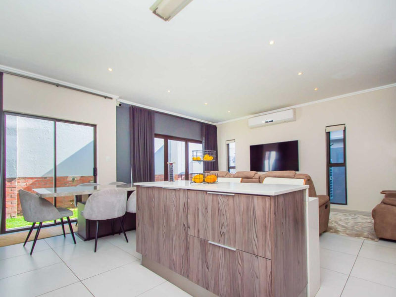 Spacious open-plan living and kitchen area featuring a modern kitchen island, tiled flooring, and sliding glass doors leading to the outdoor space.