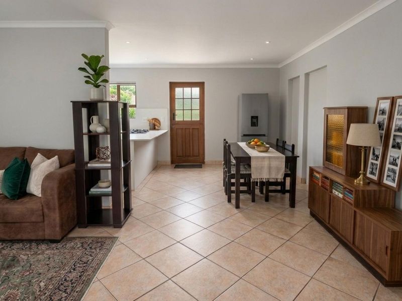 An open-plan living and dining area featuring tiled flooring, recessed lighting, and a functional kitchen space with direct access to the exterior.
