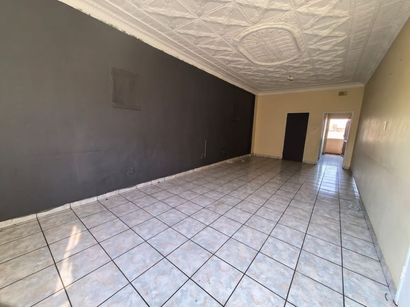 An empty living area featuring ceramic floor tiles and a decorative pressed metal ceiling, offering a blank canvas for renovation and interior design.