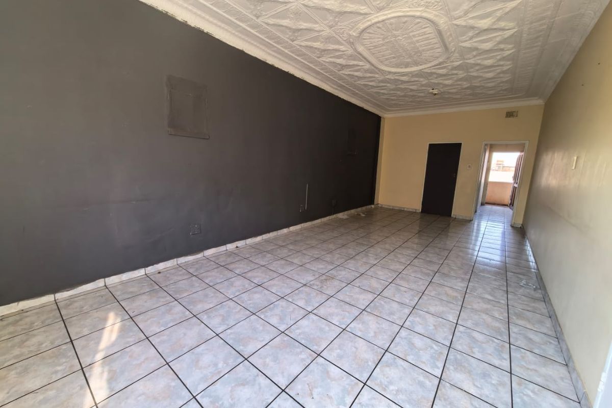 An empty living area featuring ceramic floor tiles and a decorative pressed metal ceiling, offering a blank canvas for renovation and interior design.