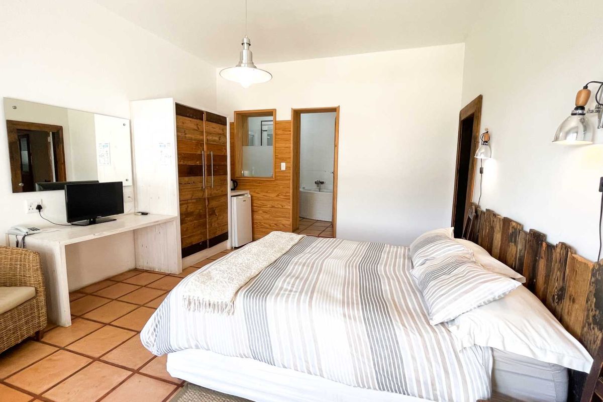 A bedroom featuring terracotta floor tiles, built-in wooden wardrobe, integrated desk space, and direct access to an en-suite bathroom.