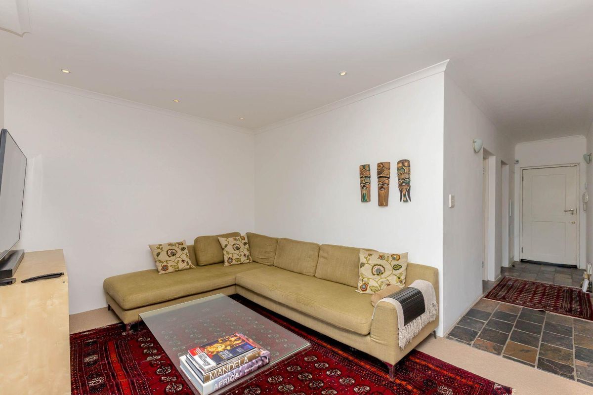 A comfortable living room featuring recessed downlights, coved ceilings, and a transition between carpeted and slate tile flooring.