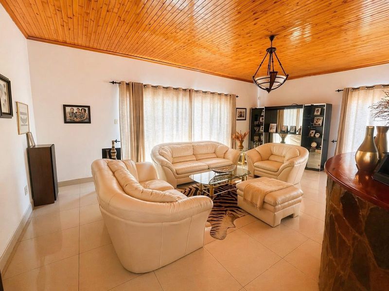 Spacious living room featuring a warm timber tongue and groove ceiling, tiled flooring, and a unique stone-clad bar counter.