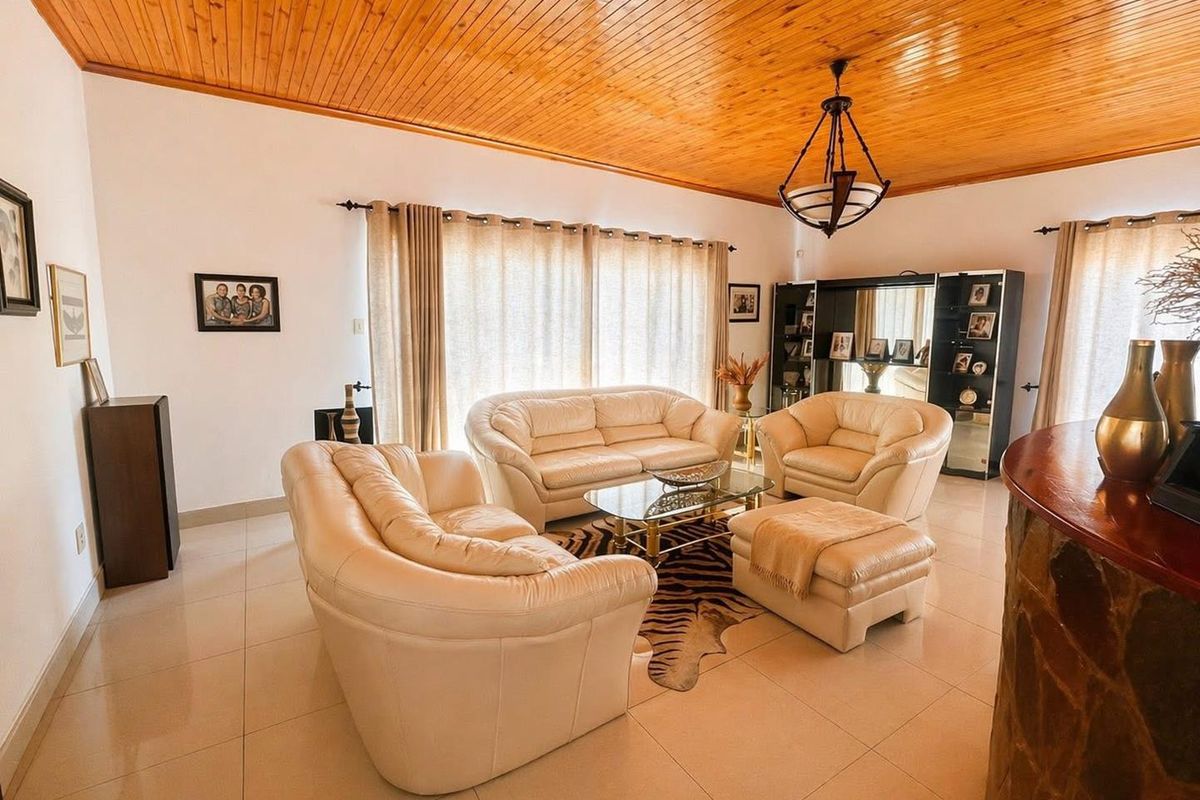Spacious living room featuring a warm timber tongue and groove ceiling, tiled flooring, and a unique stone-clad bar counter.