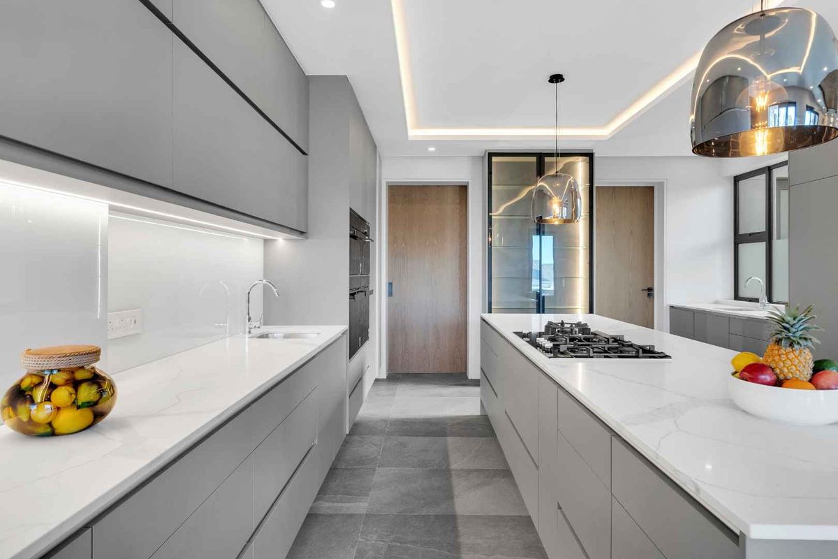 Modern, high-end kitchen featuring sleek handleless cabinetry, quartz countertops, a central island with a gas hob, and sophisticated recessed lighting.