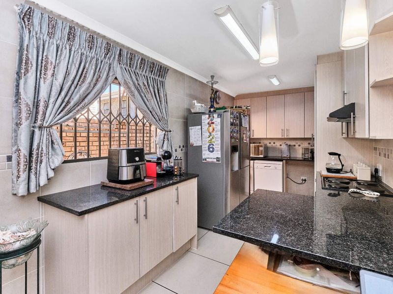 Functional kitchen featuring granite countertops, ample built-in cabinetry, tiled backsplash, and a gas hob with extractor fan, offering a practical layout for daily cooking.