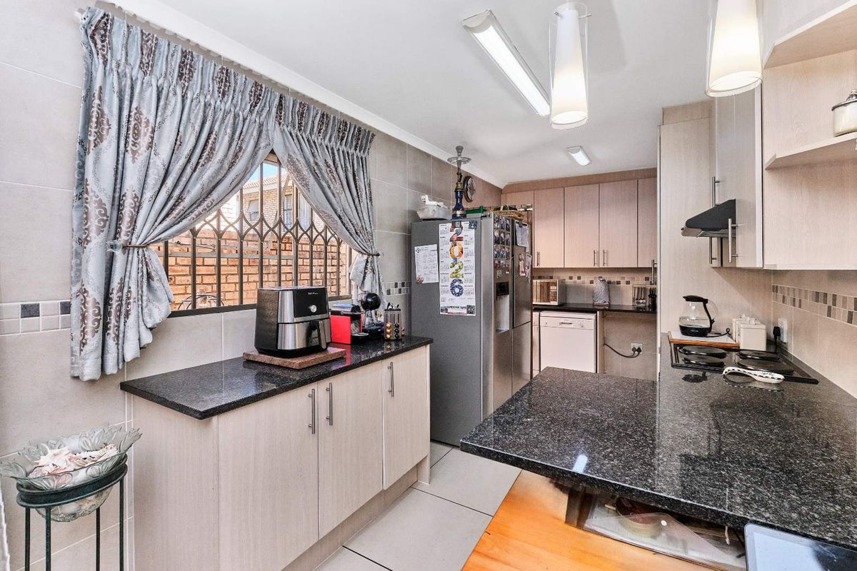 Functional kitchen featuring granite countertops, ample built-in cabinetry, tiled backsplash, and a gas hob with extractor fan, offering a practical layout for daily cooking.
