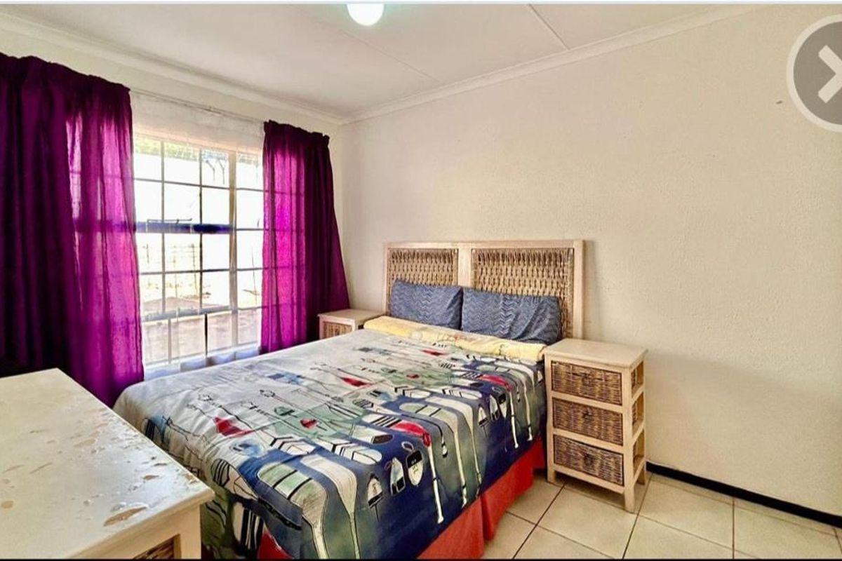 A functional bedroom featuring tiled flooring, built-in wardrobe storage, and a window with natural light.