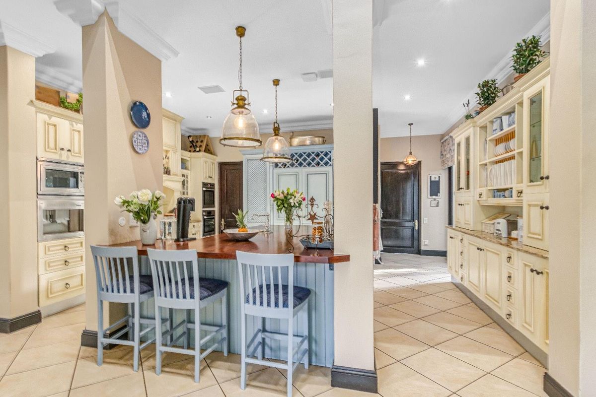 A spacious, well-appointed kitchen featuring a central island with breakfast bar seating, custom cabinetry, and tiled flooring throughout.