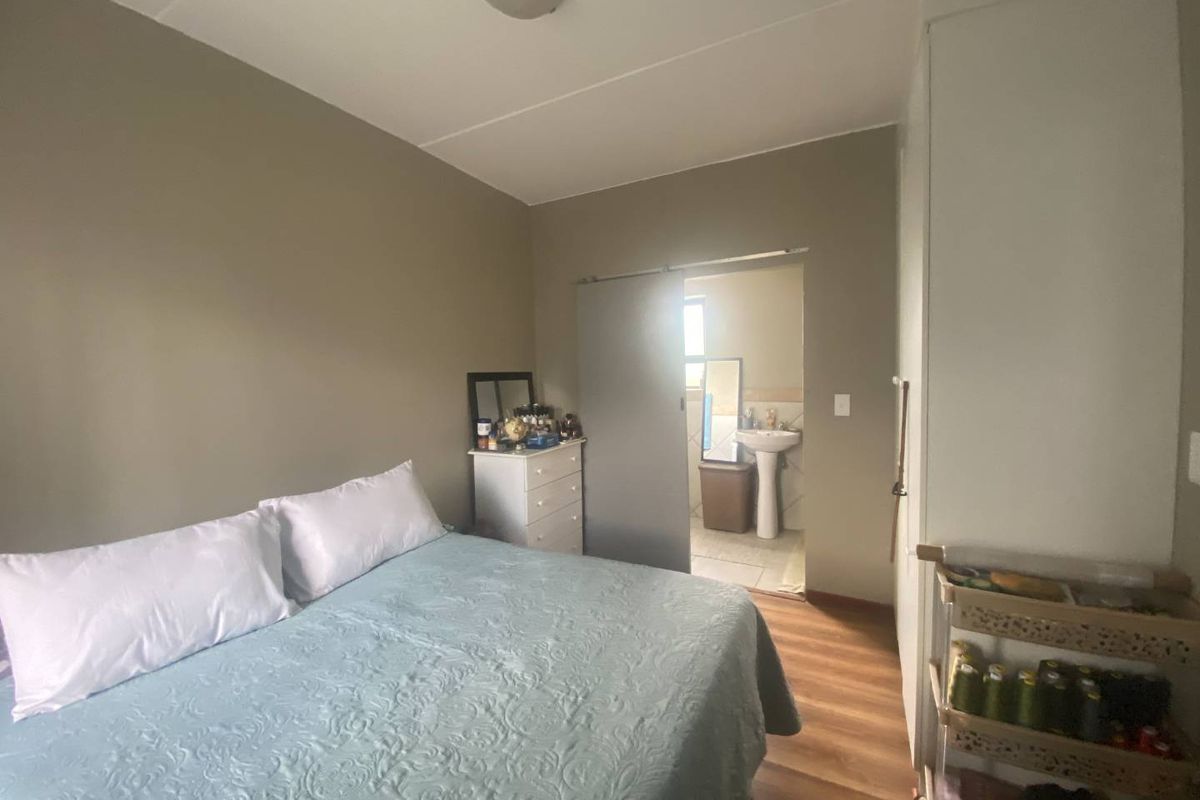 A bedroom featuring laminate flooring, a built-in cupboard, and a sliding door providing access to an en-suite bathroom.