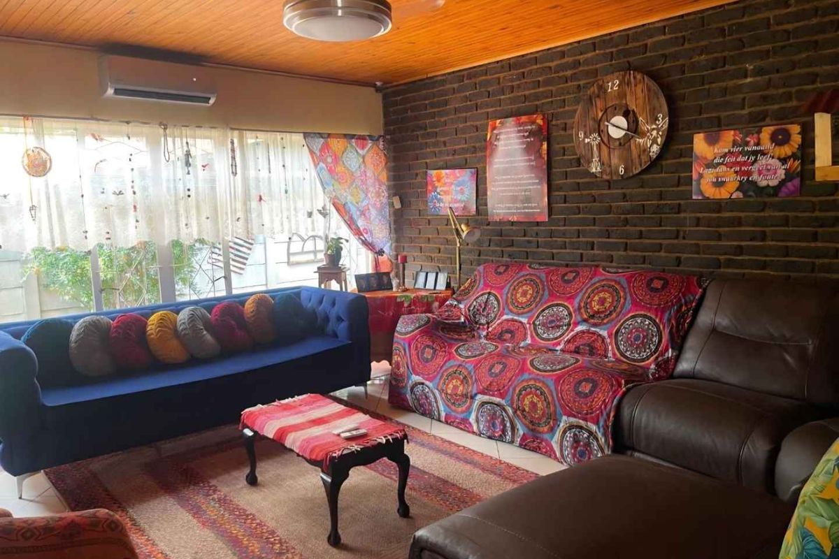 A cozy living room featuring a dark brick feature wall, timber-clad ceiling, and a wall-mounted air conditioning unit.