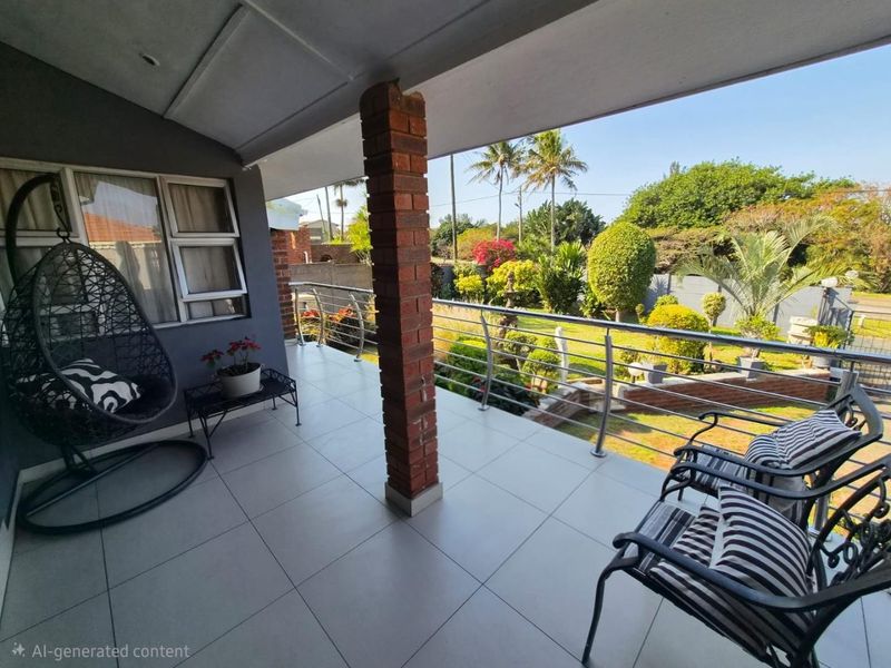 A covered balcony featuring tiled flooring, a brick support pillar, and a stainless steel balustrade overlooking a landscaped garden.