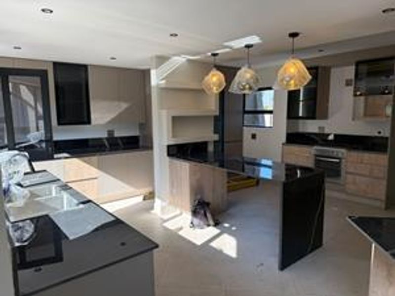 Modern, spacious kitchen featuring sleek cabinetry, stone countertops, a central island, and integrated appliances, offering a clean and contemporary culinary space.
