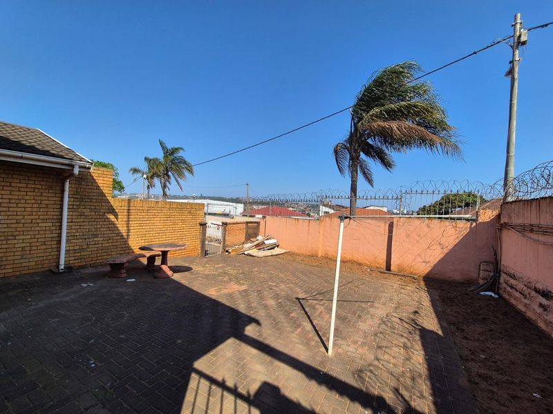 A private rear courtyard featuring brick paving, perimeter walling with security razor wire, and a rotary clothesline in an open outdoor space.