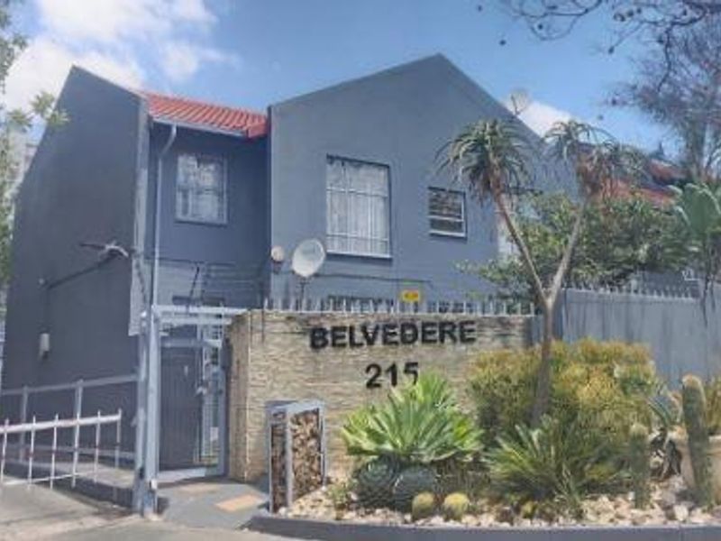 Front exterior view of the Belvedere apartment complex, featuring a gated entrance, security fencing, and stone-clad signage.
