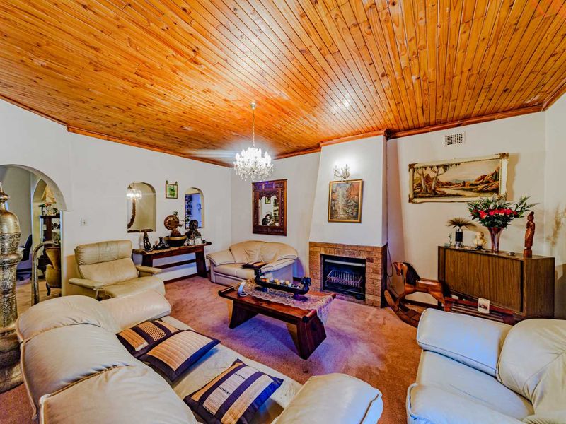 Spacious living room featuring a distinctive timber-clad vaulted ceiling, a central brick fireplace, and charming arched wall niches.