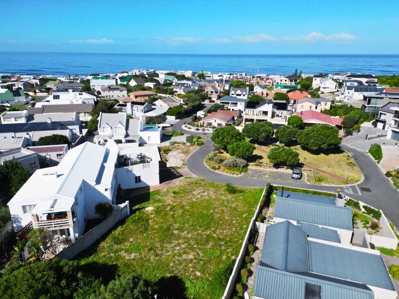 Aerial view of a vacant residential plot situated in a developed coastal neighborhood with established infrastructure and proximity to the ocean.