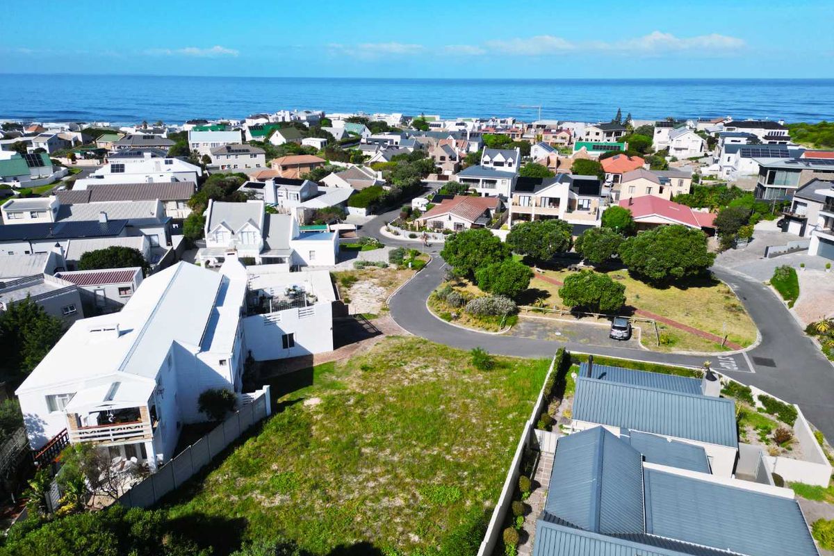 Aerial view of a vacant residential plot situated in a developed coastal neighborhood with established infrastructure and proximity to the ocean.