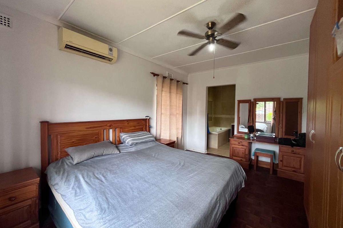 Spacious bedroom featuring parquet flooring, a ceiling fan, and an en-suite bathroom with a bathtub.