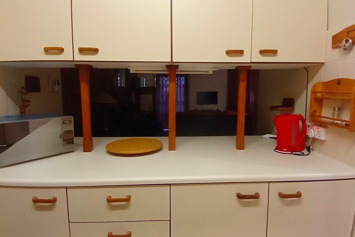 A dated kitchen area featuring laminate countertops and traditional cabinetry with wooden accents, providing a functional prep space.