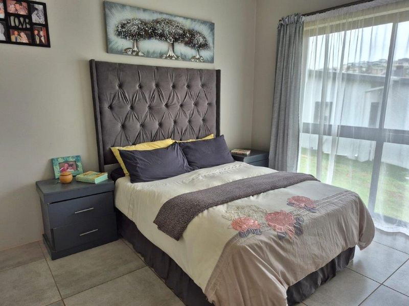 A well-maintained bedroom featuring tiled flooring and a large window that allows for natural light.