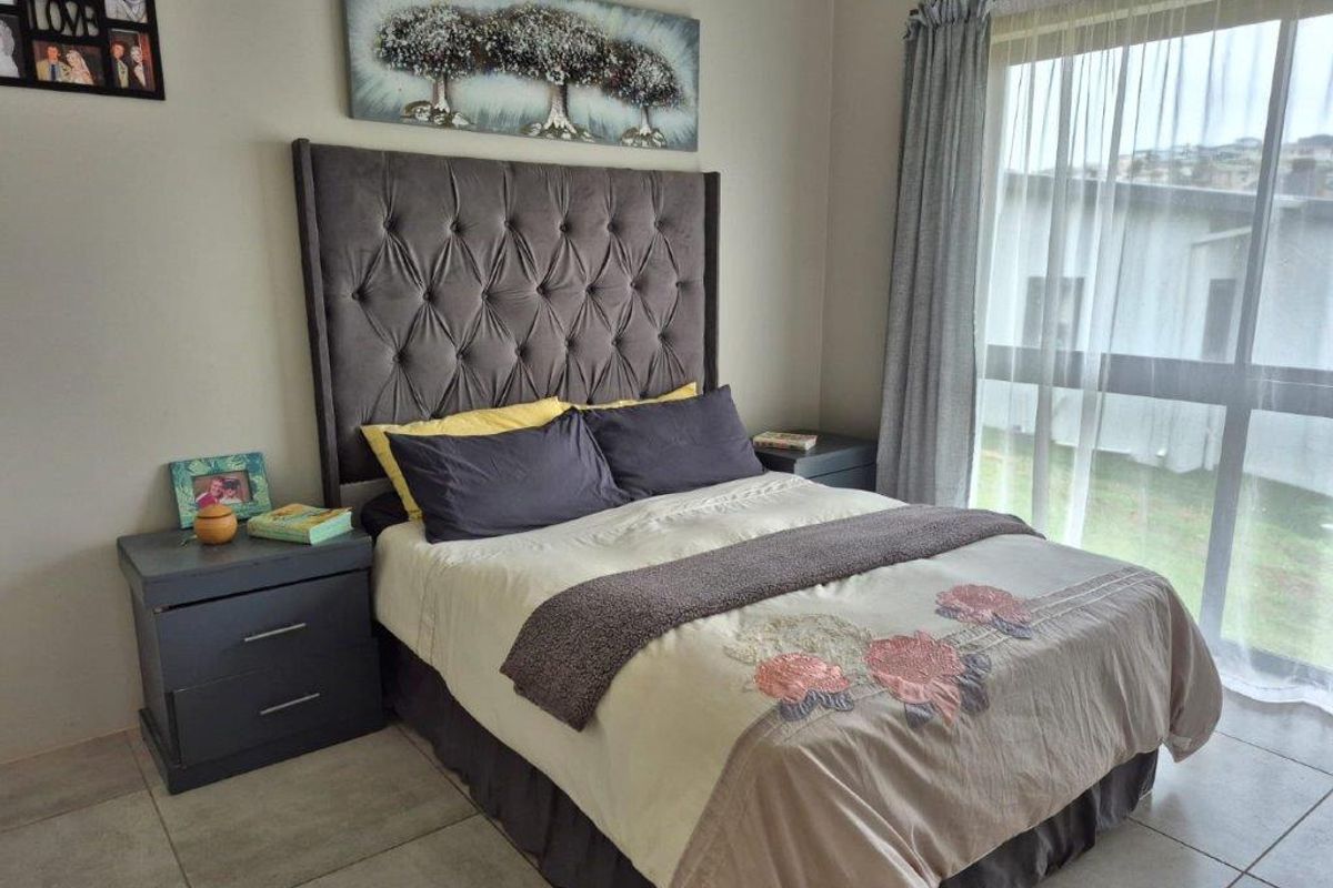 A well-maintained bedroom featuring tiled flooring and a large window that allows for natural light.