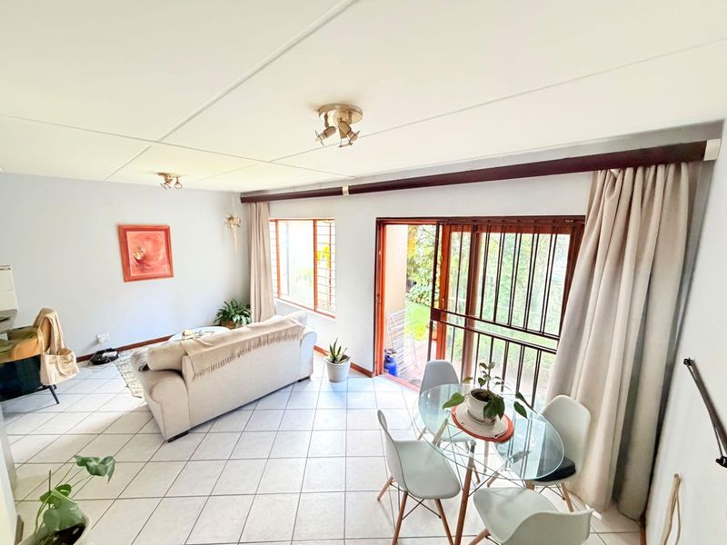 Open-plan living and dining area featuring tiled flooring, large sliding doors with security gates, and direct access to the outdoor space.