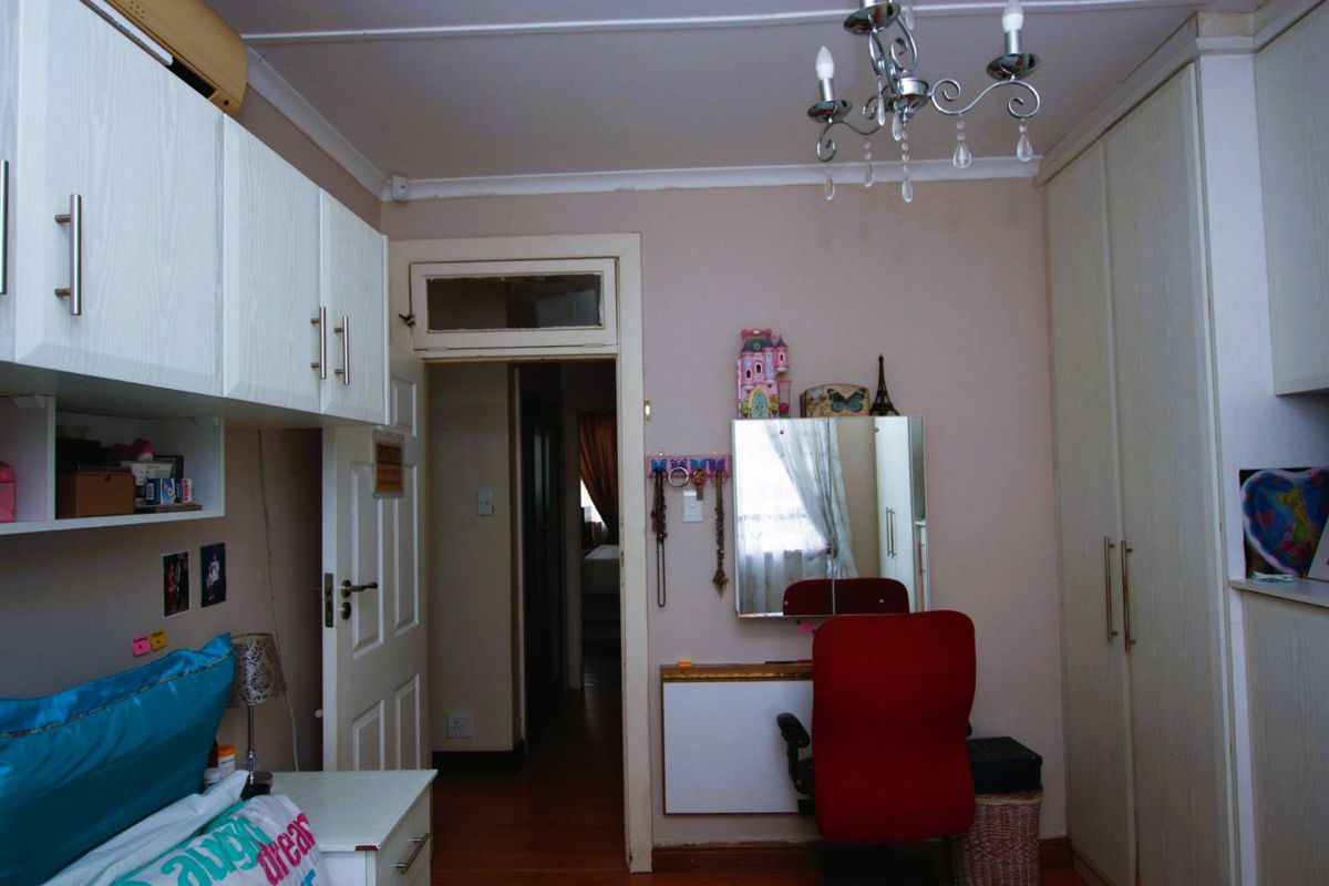 A bedroom featuring built-in cabinetry, a ceiling-mounted light fixture, and wooden flooring, providing functional storage and access to the hallway.