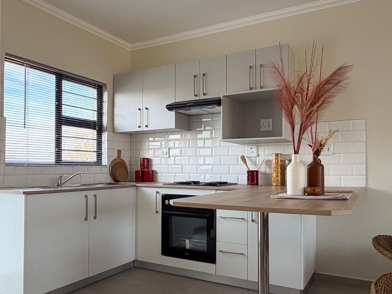 Modern kitchen featuring white cabinetry, subway tile backsplash, laminate countertops, and integrated appliances including an oven, cooktop, and extractor fan.
