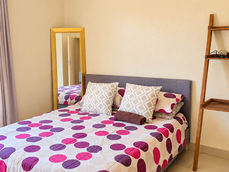 A bright bedroom featuring tiled flooring, security bars on the window, and neutral wall finishes.