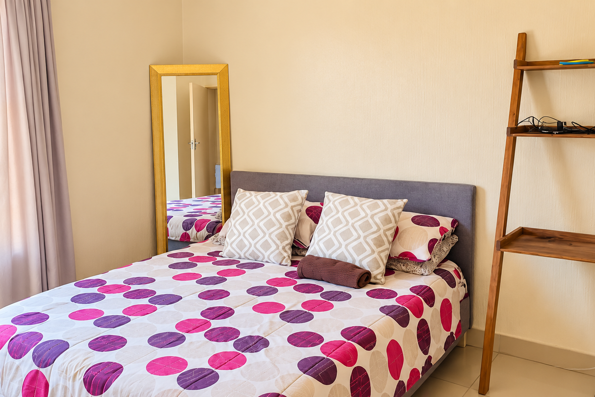 A bright bedroom featuring tiled flooring, security bars on the window, and neutral wall finishes.
