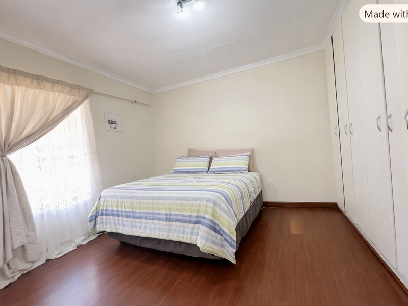 A well-maintained bedroom featuring laminate flooring, neutral walls, and extensive built-in cupboard storage.