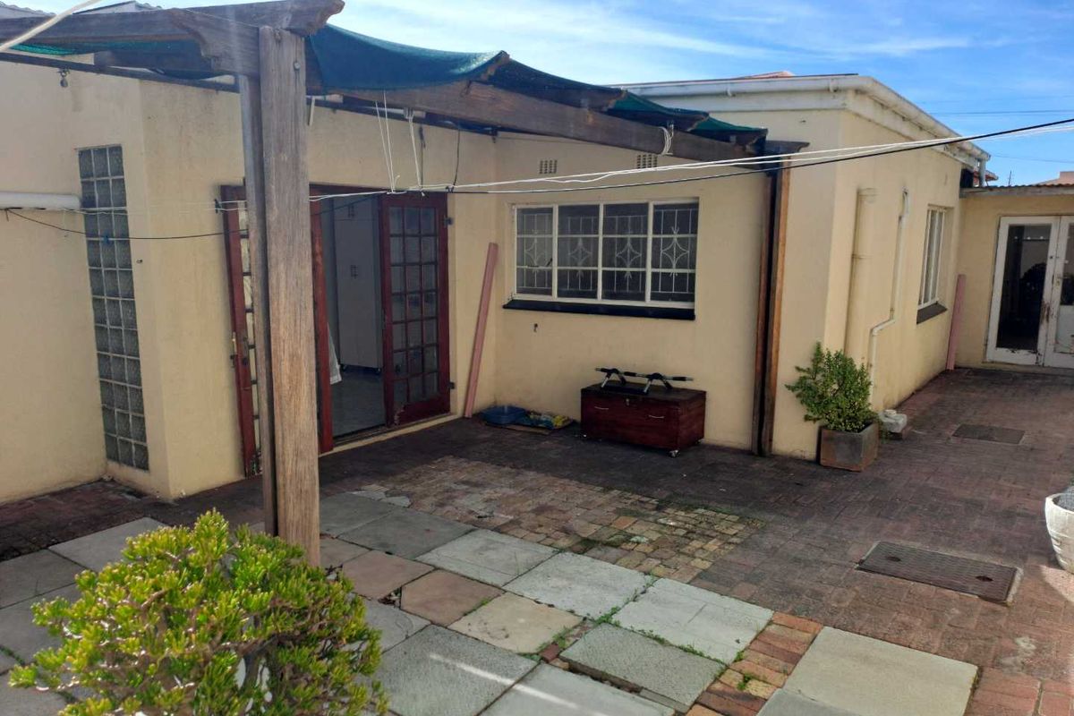 Rear exterior view featuring a paved patio area with a timber pergola structure and direct access to the home through French doors.