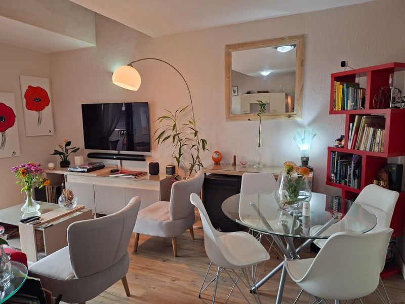 A well-lit open plan living and dining area featuring laminate flooring and neutral wall finishes, creating a comfortable and functional space.