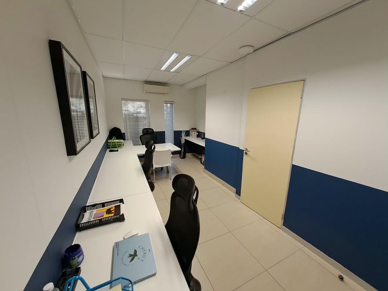A functional office space featuring tiled flooring, a built-in desk, recessed lighting, and a wall-mounted air conditioning unit.
