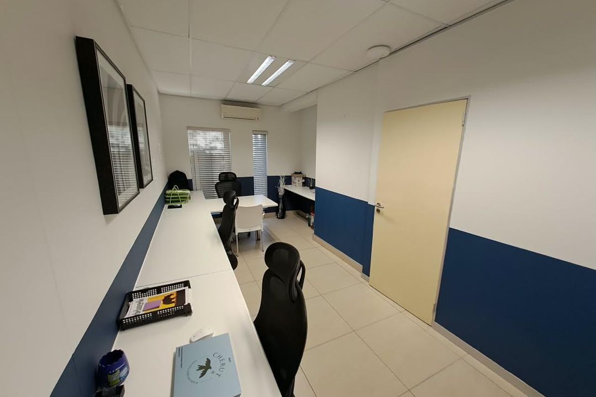A functional office space featuring tiled flooring, a built-in desk, recessed lighting, and a wall-mounted air conditioning unit.