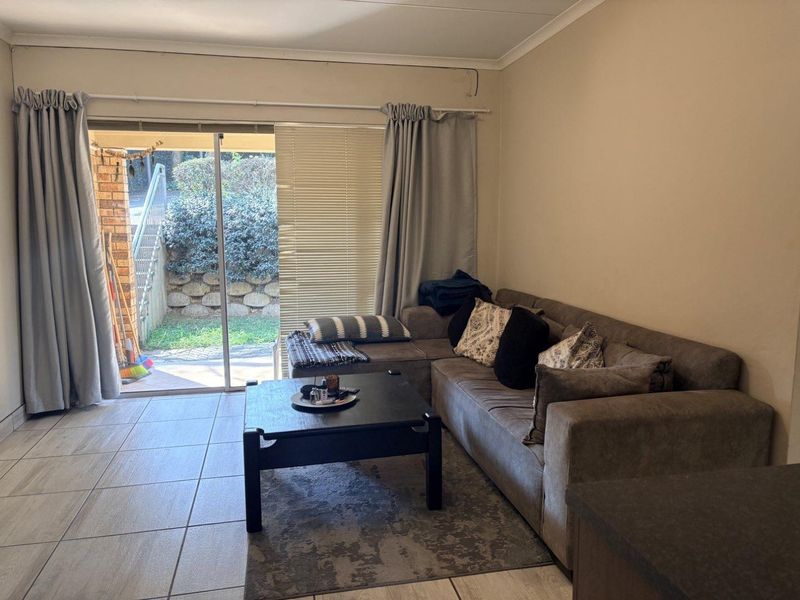 A living room featuring tiled flooring and a large sliding glass door providing direct access to an outdoor patio area.