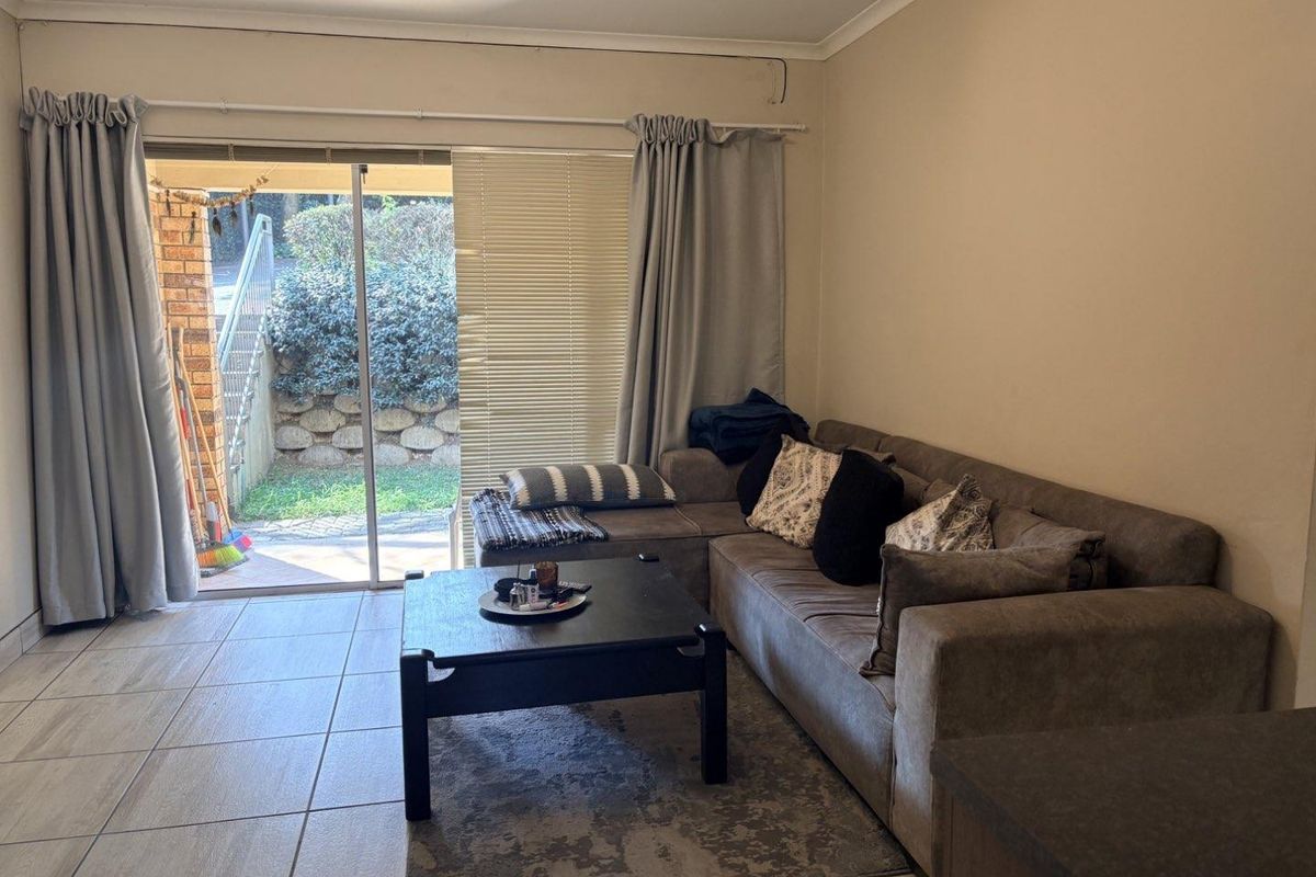A living room featuring tiled flooring and a large sliding glass door providing direct access to an outdoor patio area.