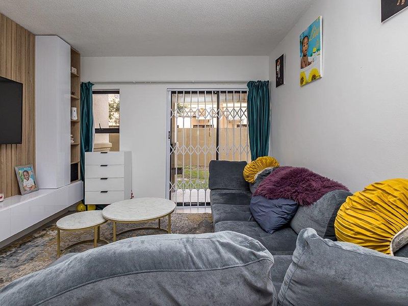 A comfortable living room featuring a modern built-in media unit and a sliding glass door with a security gate leading to the exterior.