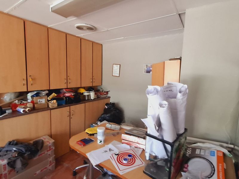 A functional office space featuring built-in wooden cabinetry, tiled flooring, and a drop ceiling, offering practical storage and workspace potential.