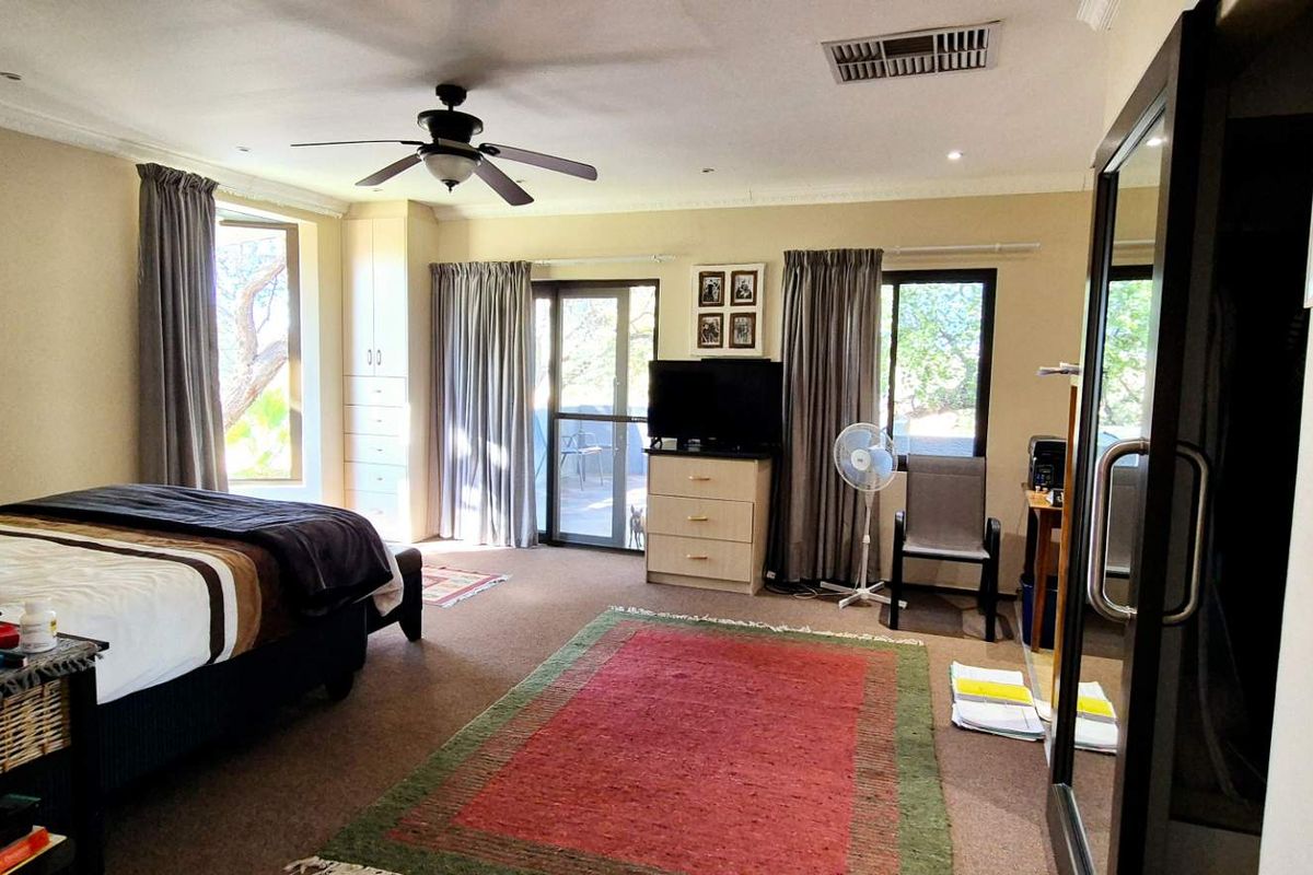 Spacious bedroom featuring built-in cabinetry, a ceiling fan, and direct access to an outdoor patio area through sliding glass doors.